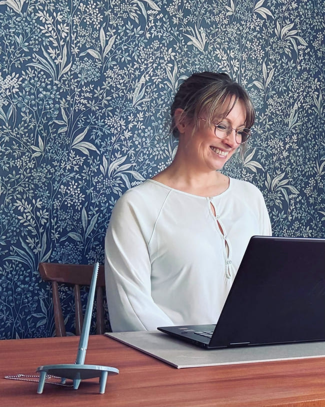 Person vid skrivbord tittar in i datorn och skrattar.