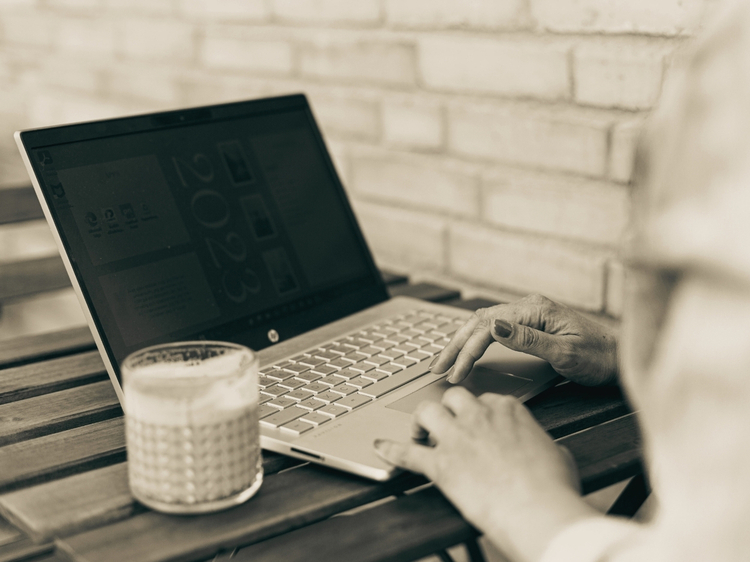 Händer vid laptop och kaffe, symboliserar att du kan ta kontakt och få svar.